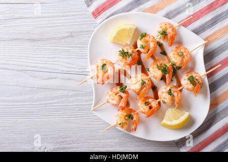 Gegrillte Garnelen am Spieß mit Zitrone auf einem Teller. horizontale Ansicht von oben Stockfoto