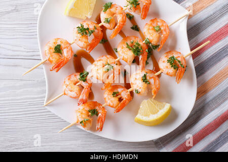 Gegrillte Garnelen am Spieß mit Zitrone auf eine Platte Nahaufnahme. horizontale Ansicht von oben Stockfoto