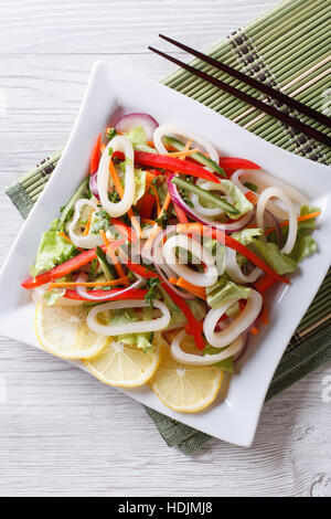 Asiatischer Salat aus Tintenfisch mit Gemüse auf einem Teller. vertikale Ansicht von oben Stockfoto