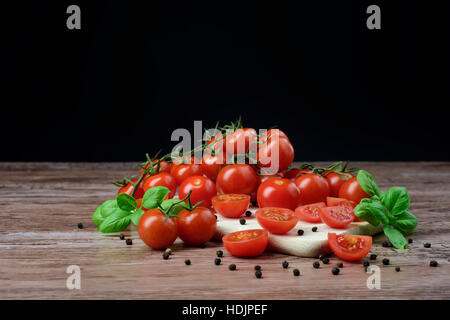 Verstreuten Cherry-Tomaten mit Basilikum-Blätter liegen auf dem Holztisch. Stockfoto