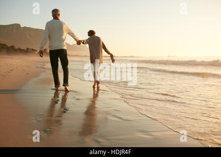 Voller Länge Rückansicht Schuss älteres Paar, die Spaß am Strand. Älteres Paar gemeinsam Urlaub im Sea Shore. Stockfoto