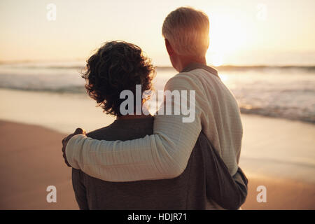 Rückansicht des Ehepaar im Ruhestand erstaunlichen Sonnenuntergang erschossen. Ältere Mann und Frau stehen zusammen am Strand. Stockfoto