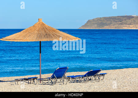 Sommer morgen kiesiger Strand mit liegen und Sonnenschirm strohig (Borsh, Albanien). Stockfoto