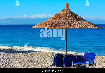 Sommer morgen kiesiger Strand mit liegen und Sonnenschirm strohig (Borsh, Albanien). Stockfoto