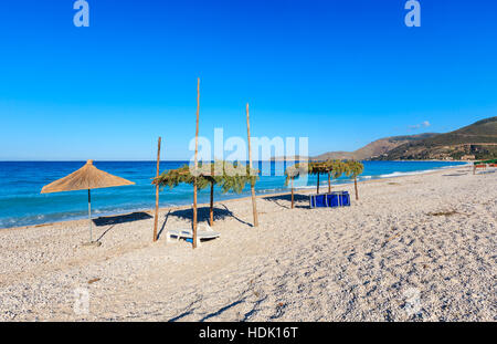 Sommer morgen kiesiger Strand mit Sonnenliegen und Baldachin (Borsh, Albanien). Stockfoto