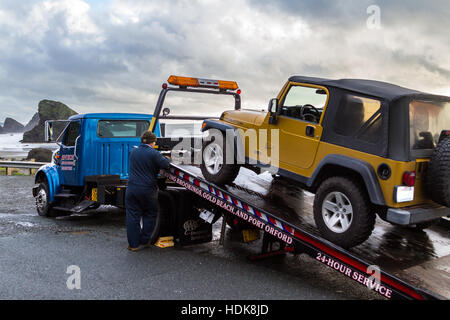 Meyers Beach, Oregon - 27 Oktober: Flachbett Abschleppwagen eine defekte Fahrzeug mit einer schönen Küstenlandschaft im Hintergrund laden. 27. Oktober 2016, Stockfoto