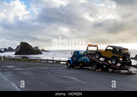 Meyers Beach, Oregon - 27 Oktober: Flachbett Abschleppwagen eine defekte Fahrzeug mit einer schönen Küstenlandschaft im Hintergrund laden. 27. Oktober 2016, Stockfoto