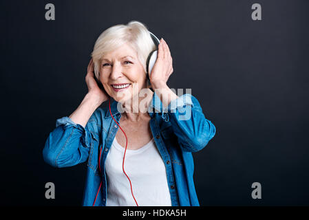 Fröhliche gealterte Frau anhören von Musik Stockfoto
