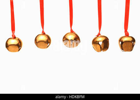 Fünf jingle Glocken hängen aus roten Bändern vor weißem Hintergrund Stockfoto