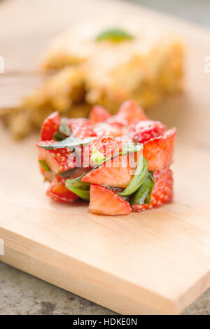 Erdbeeren und frischem Basilikum Blätter mariniert in Balsamico-Essig. Karotte-Kuchen im Hintergrund. Stockfoto