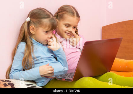 Zwei Mädchen sammeln seine Nase und einem Laptop-Bildschirm betrachten Stockfoto