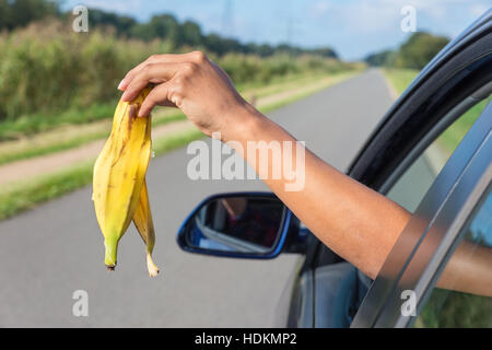 Weiblichen Arm werfen Obst Müll aus Autofenster Stockfoto