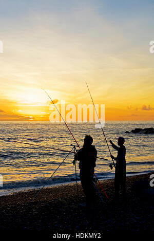 Mann und junge Angeln am Strand bei Sonnenuntergang, West Bay, Bridport, Dorset, England UK Stockfoto