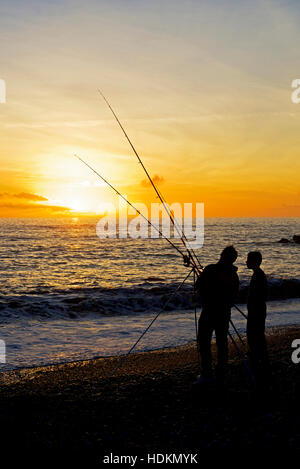 Mann und junge Angeln am Strand bei Sonnenuntergang, West Bay, Bridport, Dorset, England UK Stockfoto