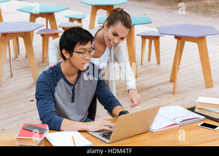 Glückliches junges Paar zeigt auf dem Bildschirm? Laptop verwenden im Café im freien Stockfoto