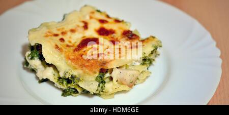 Portion hausgemachte Spinat-Lasagne mit Hühnerfleisch und Käse auf weißen Teller. Stockfoto