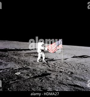 NASA Apollo 12 Mondlandung Mission Astronaut Pete Conrad entfaltet die amerikanische Flagge auf der Mondoberfläche während seiner ersten Weltraumspaziergang 19. November 1969 auf dem Mond. Stockfoto