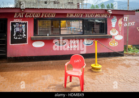 Der Imbiss „Cody's“ wirbt in Freetown mit den Worten „Eat Good Food, Enjoy You Money“ für Take-away-Mahlzeiten, davor steht ein roter Plastikstuhl. Western Area, Sierra Leone Stockfoto