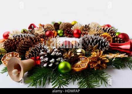 Weihnachts-Dekoration mit Glas und Holz Glöckchen. Weihnachtsgruß Hintergrund mit roten Ornamenten verziert Kranz. Stockfoto