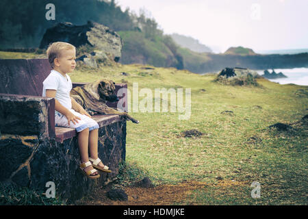 Kind und Hund auf einer Bank sitzen und Blick aufs Meer Stockfoto