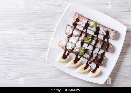 Schokolade Crepes mit Soße und Bananen auf einen Teller. horizontale Ansicht von oben Stockfoto