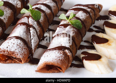 Schokolade Crepes mit Sauce und Bananen Nahaufnahme auf einer Platte. horizontale Stockfoto