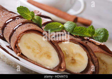 Schokolade Crepes mit Bananen Füllung Nahaufnahme auf einem weißen Teller. horizontale Stockfoto
