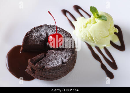 Schokoladen-Fondant Kuchen mit Kirschen und Minze-Eis auf eine Platte Nahaufnahme. horizontale Ansicht von oben Stockfoto