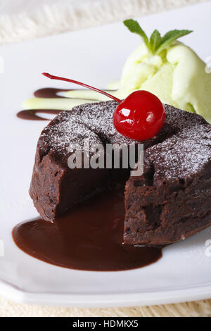 Schokoladen-Fondant Kuchen mit Kirschen und Minze-Eis auf eine Platte Nahaufnahme. vertikale Stockfoto