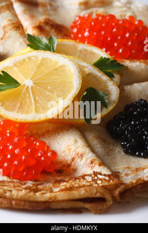 Dünne Crepes mit roten und schwarzen Kaviar auf einem Teller Makro vertikalen Stockfoto