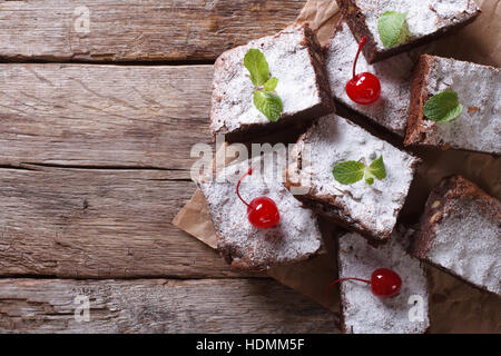 Brownie-Kuchen mit Minze und Kirsche auf dem Papier. horizontale Ansicht von oben, rustikalen Stil Stockfoto