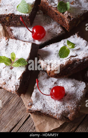 Schokoladenkuchen-Brownies mit Minze und Kirsche Closeup auf Papier. vertikale Stockfoto