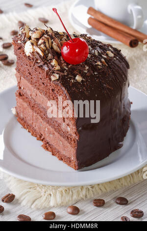 Ein Stück Schokoladenkuchen mit Kirschen auf einer Platte. Vertikale Nahaufnahme Stockfoto