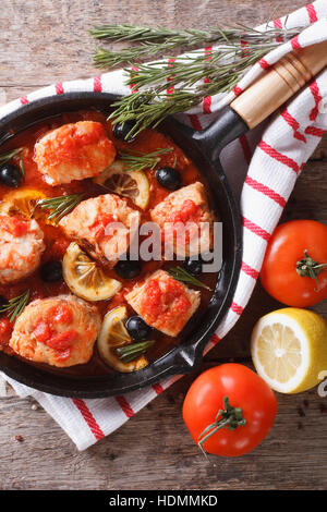 Fisch in Tomatensauce mit Oliven und Zitrone in einer Pfanne erhitzen. vertikale Ansicht von oben Stockfoto