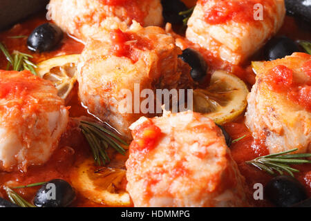 Weiße Fischfilets in Tomatensoße mit Zitrone und Oliven Makro. horizontale Stockfoto