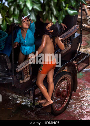 Zwei jungen kambodschanischen Khmer Kinder spielen im Regen Tropfen Schuppen von Baum-Blätter in Siem Reap, Kambodscha zu fangen. Stockfoto