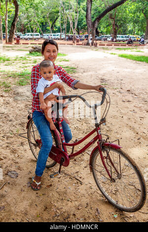 Eine junge kambodschanische Mutter reitet ihr Baby Boy auf ihre roten, Fromage Fahrrad, die beliebteste Form des Transportes in Kambodscha. Stockfoto