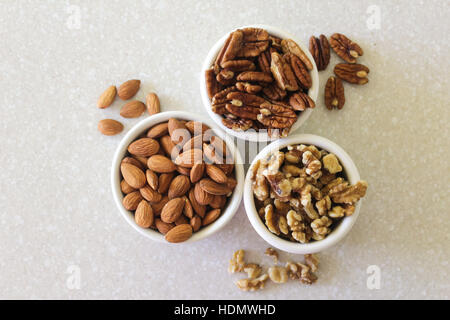 Köstliche Mandeln, Pekannüsse und Walnüssen in Containern auf einer Küchenarbeitsplatte bereit, um als Snack oder in ein Lieblingsrezept zu genießen! Portfolio für Oth ansehen Stockfoto