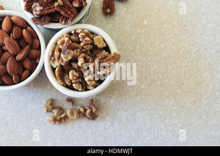 Köstliche Mandeln, Pekannüsse und Walnüssen in Containern auf einer Küchenarbeitsplatte bereit, um als Snack oder in ein Lieblingsrezept zu genießen! Portfolio für Oth ansehen Stockfoto