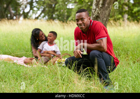 Glückliche schwarze Menschen im Stadtpark. Afroamerikanische Familie mit jungen Vater, Mutter und Sohn beim Picknick. Freizeit für Mann, Frau und Sohn. Stockfoto