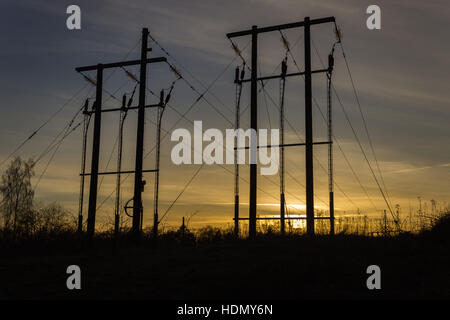 Silhouetten von Stromleitungen in einem Szenario mit Sonnenuntergang Stockfoto