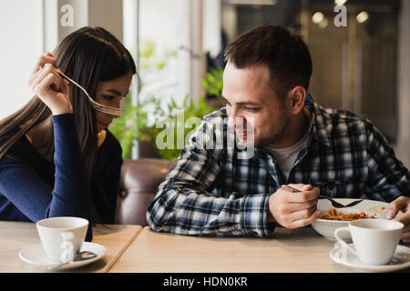 Lustige paar essen Nudeln im Café. Er will nicht seine Nahrung mit Freundin teilen Stockfoto