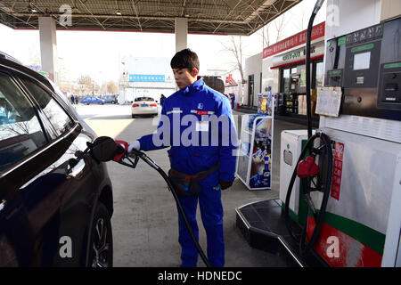 Shijiazhuang, Shijiazhuang, China. 14. Dezember 2016. Ein Arbeiter hilft ein Auto an einer Tankstelle in Shijiazhuang, Hebei-Provinz Nord-China, 14. Dezember 2016 zu tanken. China sah seine größte Benzin- und Dieselpreise in den vergangenen vier Jahren spät vor kurzem angetrieben die Ausgabe schneiden durch OPEC und anderen Herstellern erhöhen. Preise für Benzin und Diesel wurden von 435 Yuan ($63) und 420 Yuan pro Tonne, bzw. nach einer Meldung von der National Development and Reform Commission am 14. Dezember 2015 gewandert. Es war der 24. Preisanpassung für dieses Jahr. (Kredit-Bild: © SIPA Asien vi Stockfoto