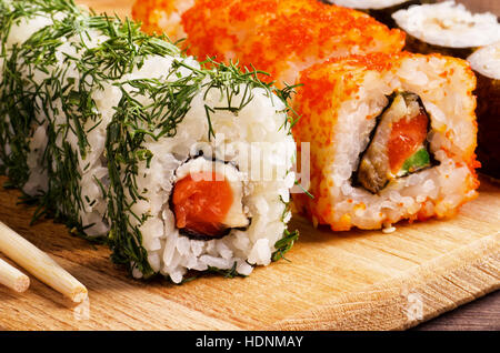 Japanisches Essen, Brötchen Lachs Sushi Set auf einem Küchentisch mit Stäbchen Stockfoto