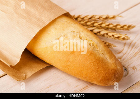 Baguette-Brot mit Ähren auf einem hölzernen Hintergrund Stockfoto