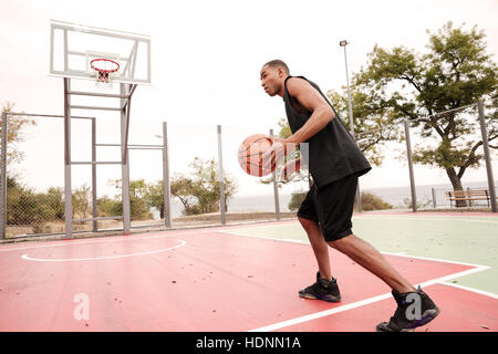 Foto des jungen afrikanischen Basketball-Spieler üben. Auf der Suche zur Seite. Stockfoto