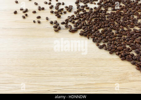 Frisch geröstete Kaffeebohnen ausgebreitet auf hölzernen Hintergrund Stockfoto