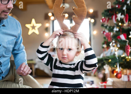 Vater mit stahlharte am Weihnachtsbaum, Rentier-Geweih tragen Stockfoto