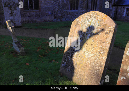 Ein Schatten auf, einen Grabstein von der Statue einer engelhaften Figur auf einem Friedhof. Stockfoto