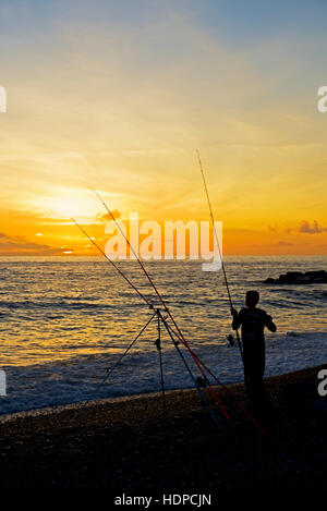 Junge, Fischen am Strand bei Sonnenuntergang, West Bay, Bridport, Dorset, England UK Stockfoto